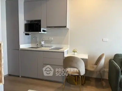 Modern compact kitchen with sleek cabinetry and cozy dining area in a stylish apartment.