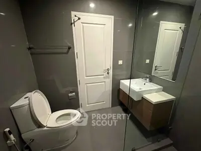 Modern bathroom with sleek design featuring a wall-mounted sink and glass shower enclosure.
