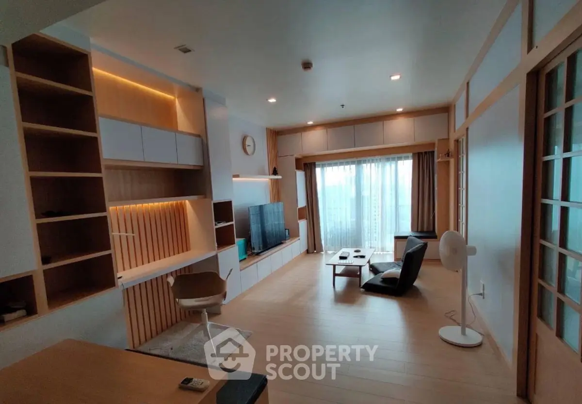Modern living room with sleek furniture and large window offering natural light.