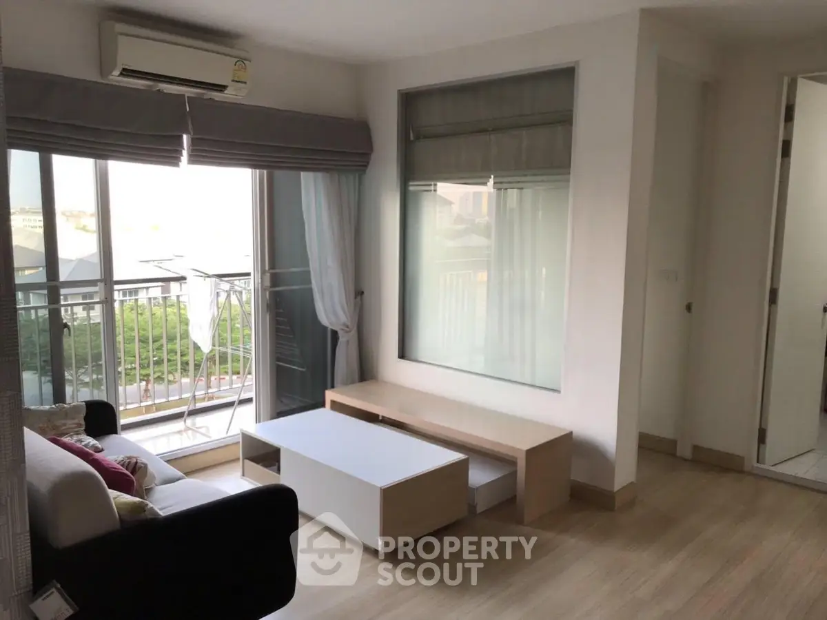 Modern living room with balcony view, featuring sleek furniture and natural light.