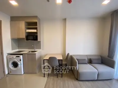 Modern living room with compact kitchen and washing machine, ideal for urban living.