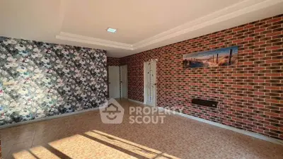 Spacious living room with unique brick and floral wallpaper design, ample natural light.