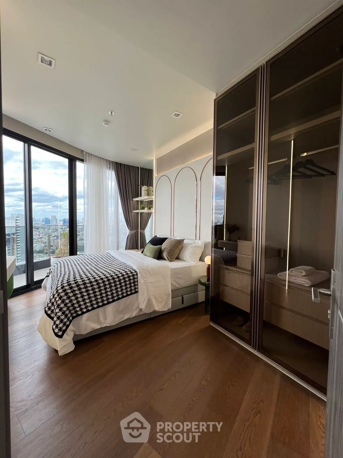 Luxurious bedroom with city view, elegant decor, and spacious wardrobe.