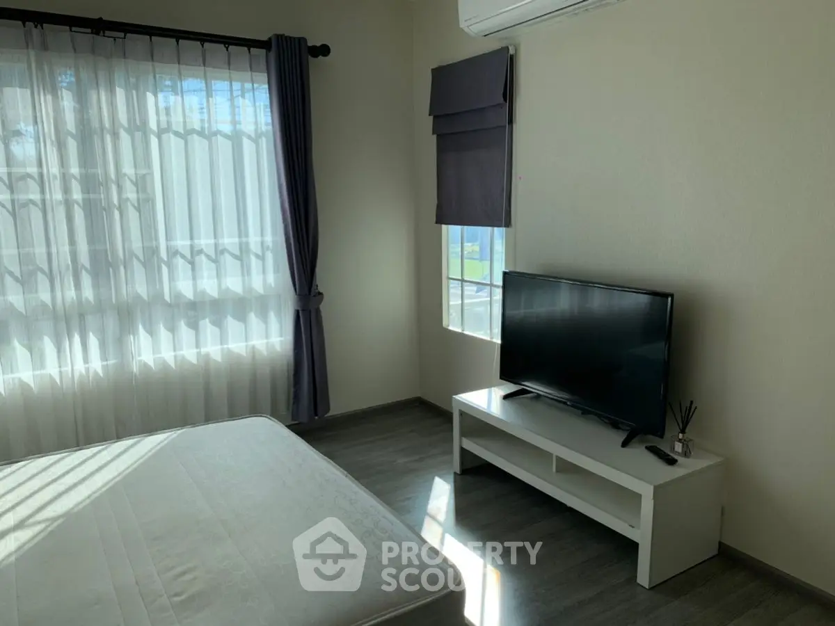 Bright bedroom with large window, TV, and air conditioning unit, perfect for modern living.