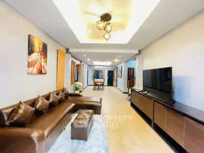 Spacious modern living room with elegant decor and large TV, perfect for relaxation and entertainment.