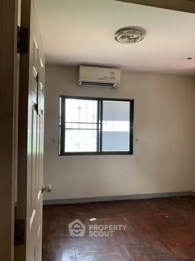 Spacious room with wooden flooring and air conditioning unit, ideal for customization.