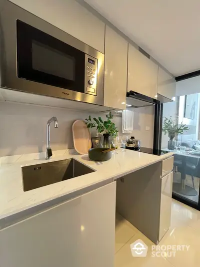 Modern kitchen with sleek cabinetry, built-in microwave, and elegant marble countertop