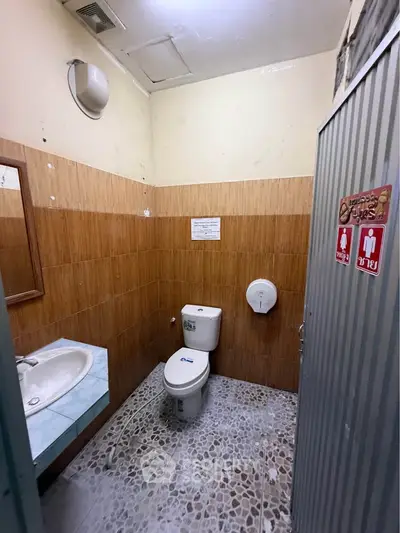 Compact bathroom with tiled walls and floor, featuring a toilet and sink.