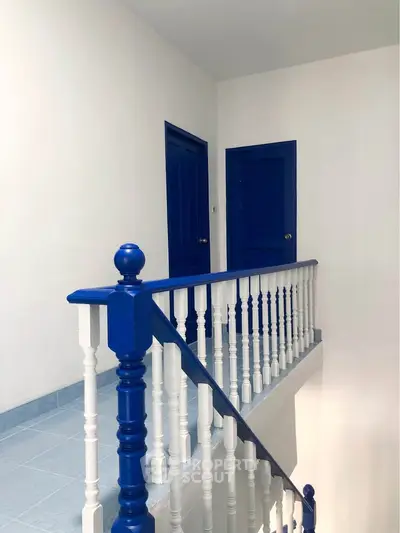 Bright hallway with blue doors and railing, showcasing modern interior design.