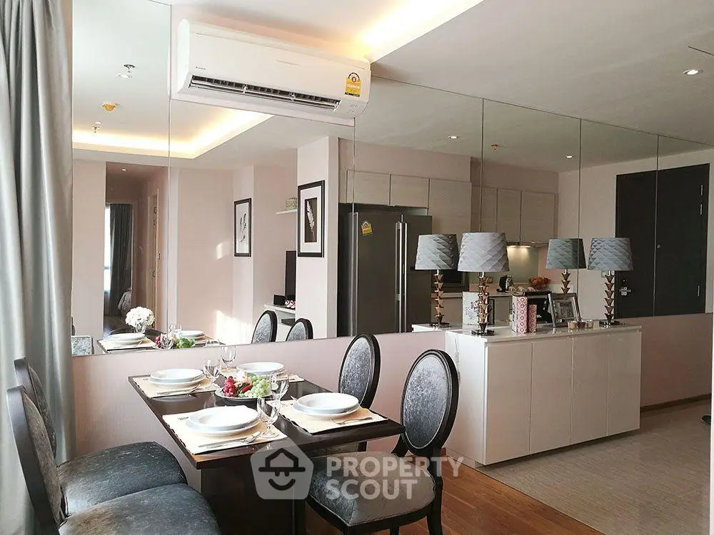 Modern dining area with elegant table setting and mirrored wall in stylish apartment.