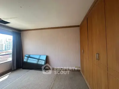 Spacious room with built-in wooden wardrobe and large window view