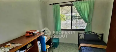 Cozy bedroom with single bed, desk, and window view in a compact space.