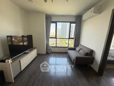 Modern living room with large window and city view, featuring sleek furniture and air conditioning.