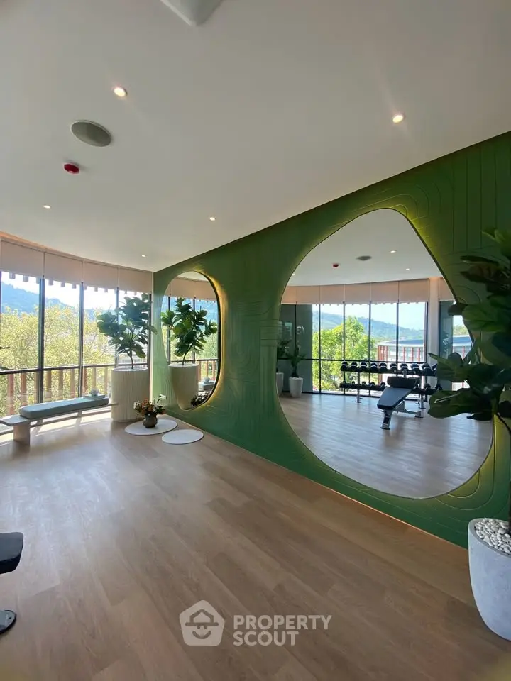 Luxurious gym with modern design and panoramic views, featuring large mirrors and lush greenery.