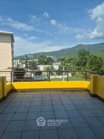 Spacious balcony with stunning mountain views and vibrant yellow railing.