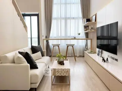 Modern living room with high ceilings, large windows, and stylish decor in a contemporary apartment.