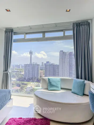 Stunning city view from modern living room with round sofa and large windows.