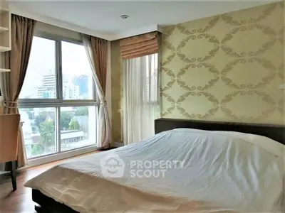 Spacious bedroom with large windows offering city views and elegant wallpaper design.