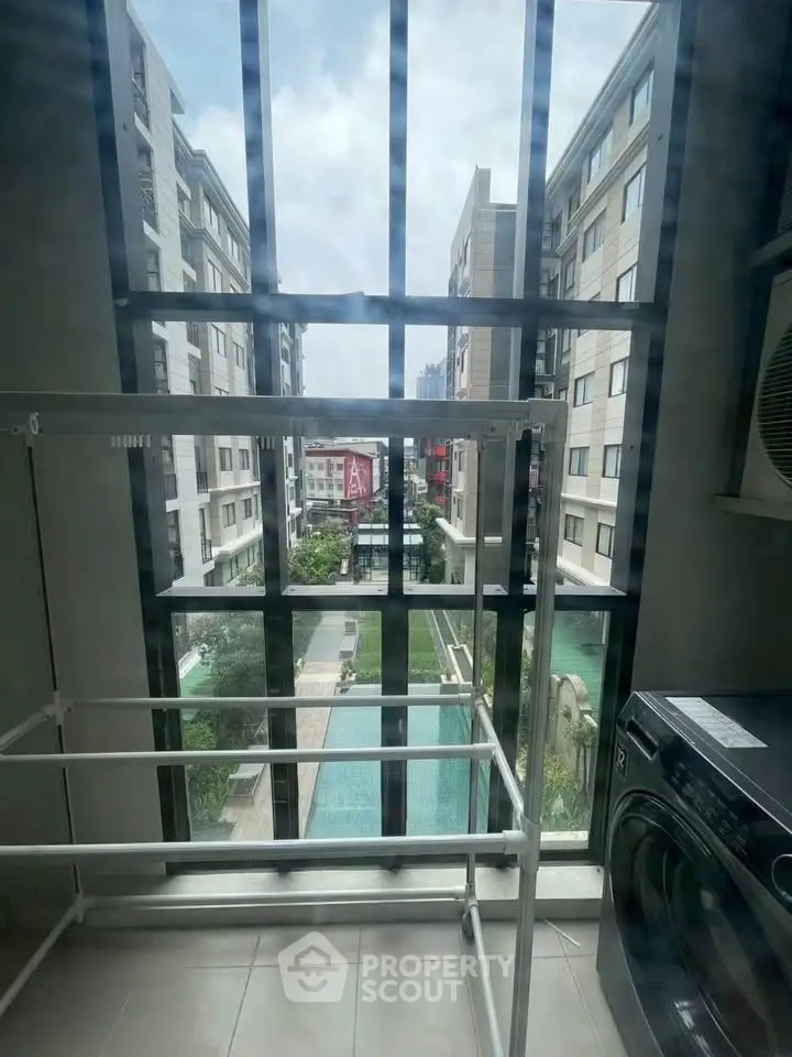 Modern apartment view with large windows overlooking courtyard and pool