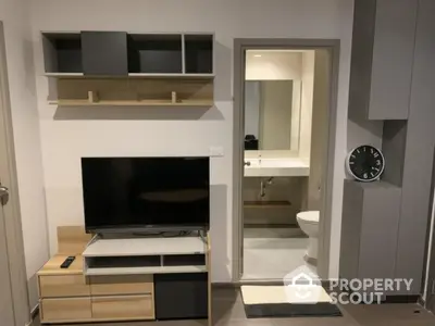 Modern living room with sleek TV unit and view into minimalist bathroom