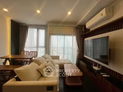 Modern living room with large TV, cozy sofa, and dining area in a stylish apartment.