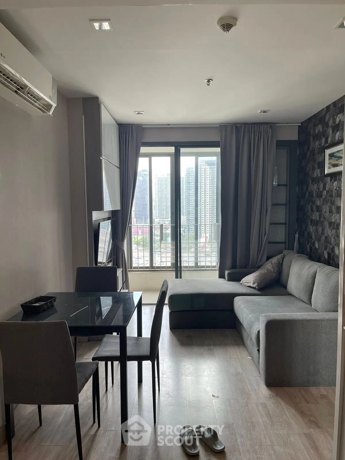 Modern living room with city view, featuring sleek furniture and large windows for natural light.