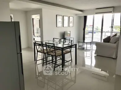 Spacious modern living room with glass dining table and large windows.