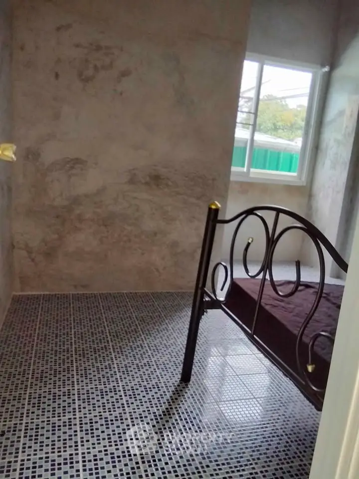 Cozy bedroom with metal bed frame and tiled flooring, featuring a window view.