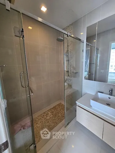 Modern bathroom with glass shower and sleek vanity in contemporary apartment.