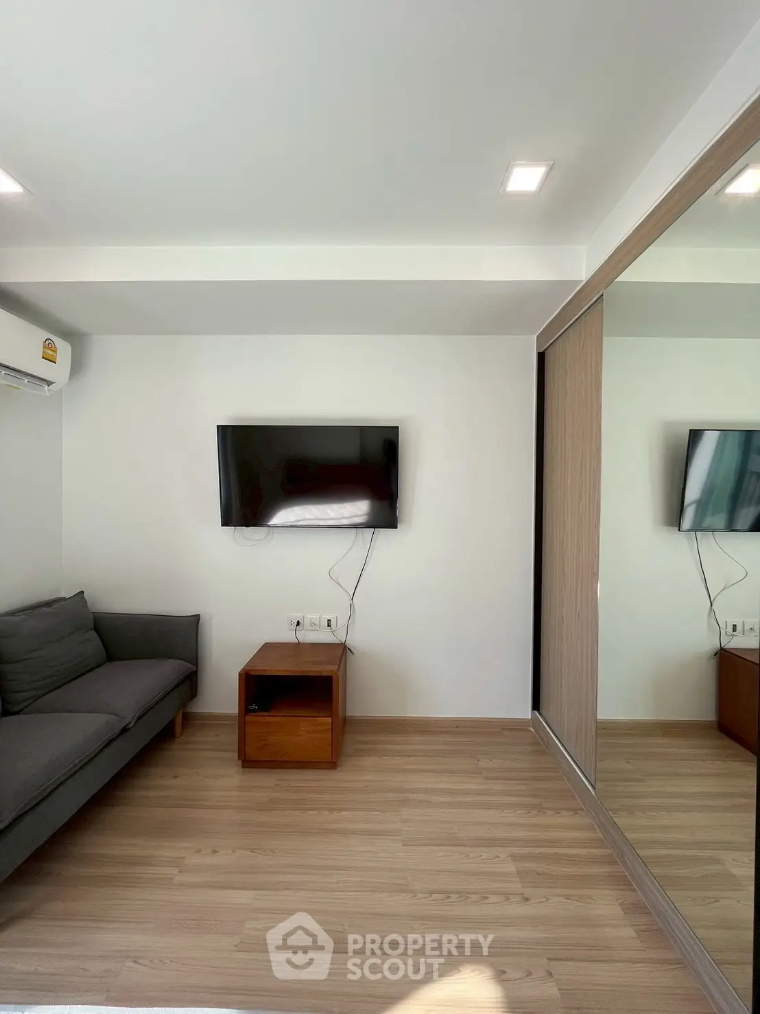 Modern living room with wall-mounted TV and mirrored wardrobe