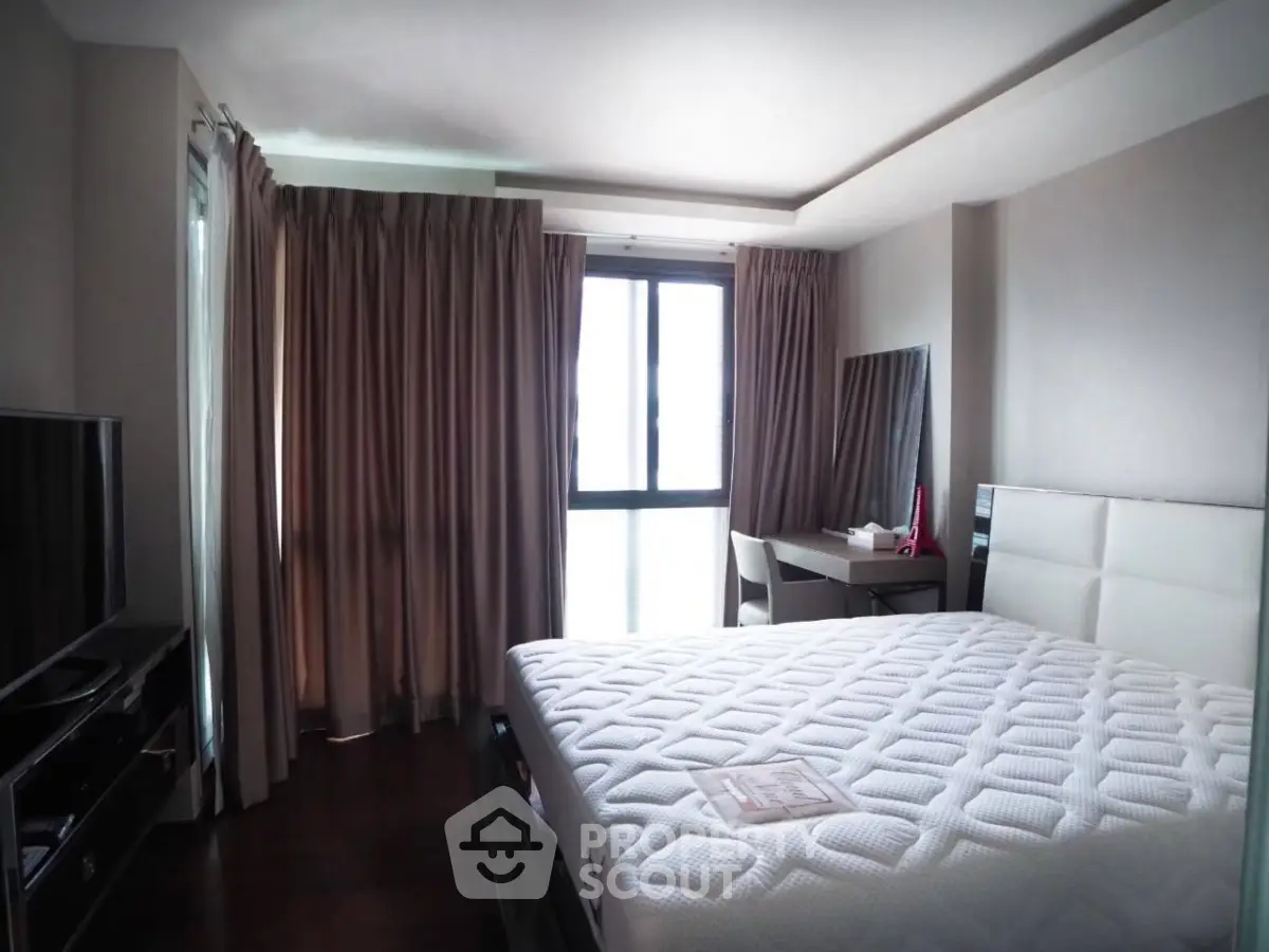 Spacious bedroom with modern furnishings and large window for natural light.
