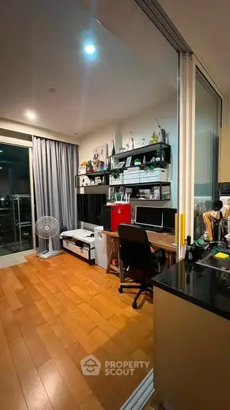 Modern study room with wooden flooring and balcony access in a stylish apartment.
