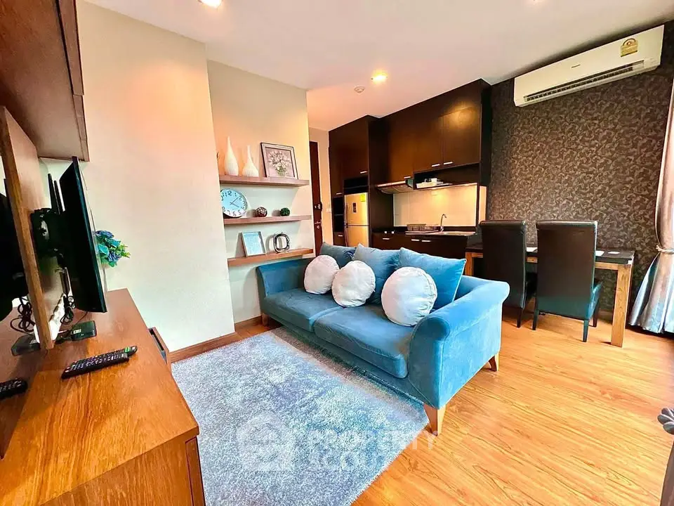 Modern living room with blue sofa and stylish kitchen in open layout apartment.