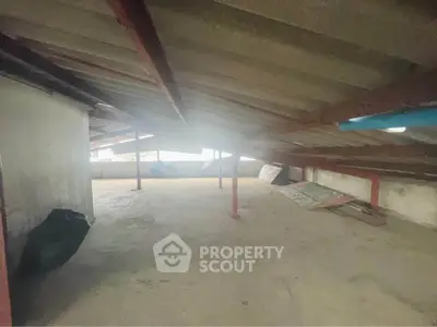 Spacious attic space with sloped ceiling and natural light, ideal for storage or renovation.