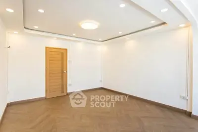 Spacious empty room with elegant wooden flooring and modern recessed lighting.