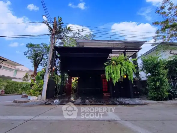 Modern house exterior with lush greenery and sleek design in a suburban neighborhood.