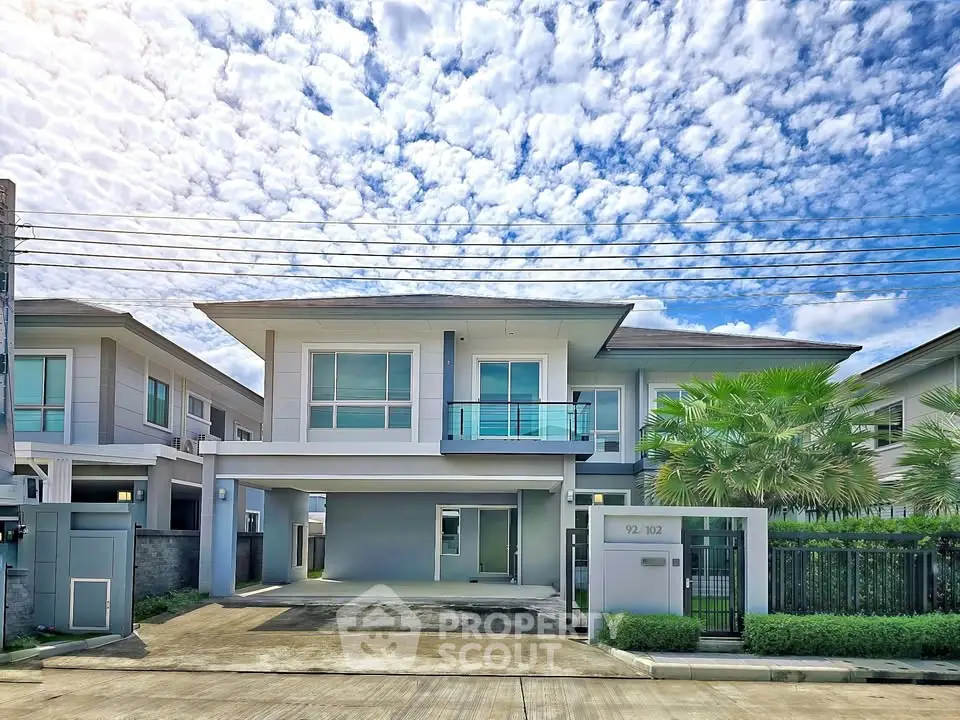 Modern two-story house with driveway and lush greenery under a vibrant sky.