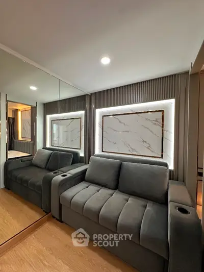 Modern living room with sleek gray sofa and mirrored wall accents