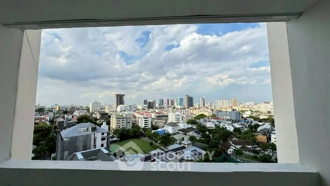 Stunning cityscape view from a high-rise building window, showcasing urban skyline and blue sky.