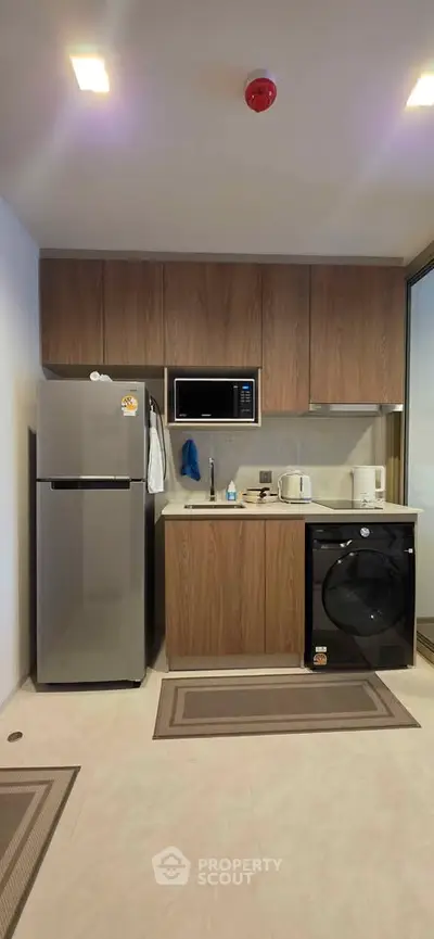 Modern kitchen with sleek appliances and wooden cabinetry in a stylish apartment.