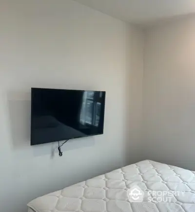 Minimalist bedroom with wall-mounted TV and comfortable mattress