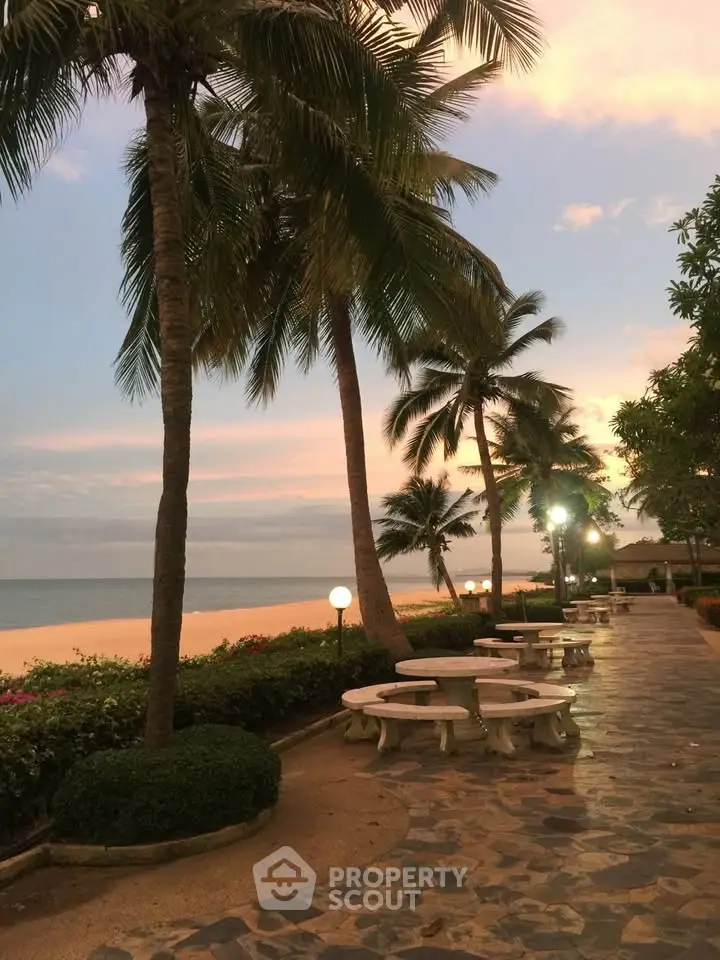 Stunning beachfront walkway with palm trees and ocean view at sunset.
