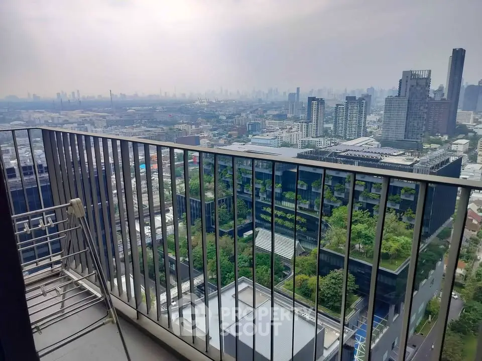 Stunning cityscape view from a high-rise balcony overlooking urban skyline and lush green rooftops.