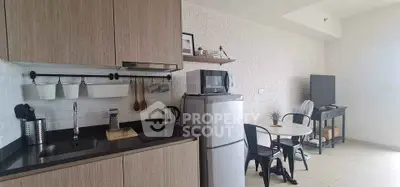 Modern kitchen with sleek cabinetry and cozy dining area in open layout apartment.