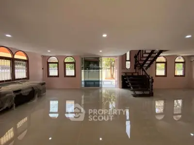 Spacious open-plan living area with elegant staircase and large windows