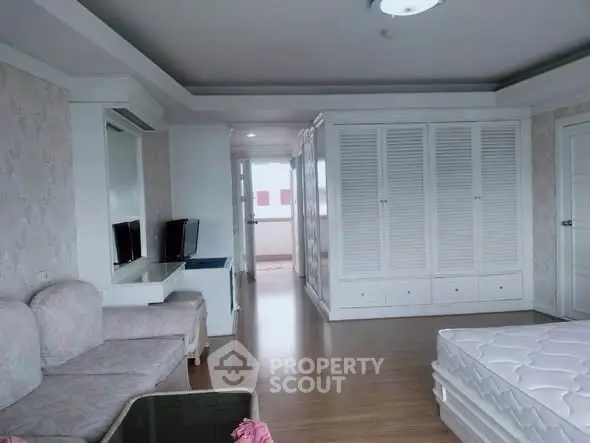 Spacious bedroom with elegant white wardrobes and cozy seating area, perfect for relaxation and comfort.