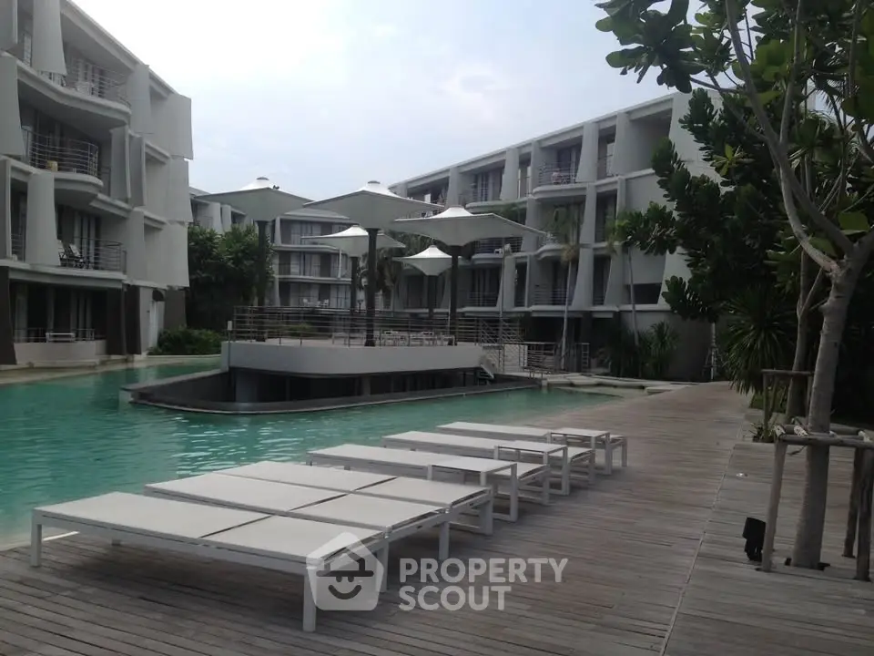 Luxurious modern apartment complex with poolside relaxation area and stylish architecture.
