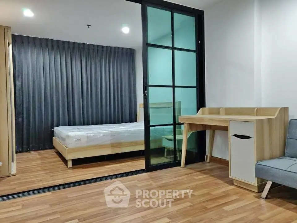 Modern bedroom with sliding glass doors and wooden flooring in a stylish apartment.