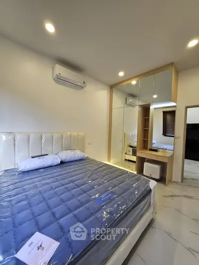 Modern bedroom with mirrored wardrobe and air conditioning in a stylish apartment.