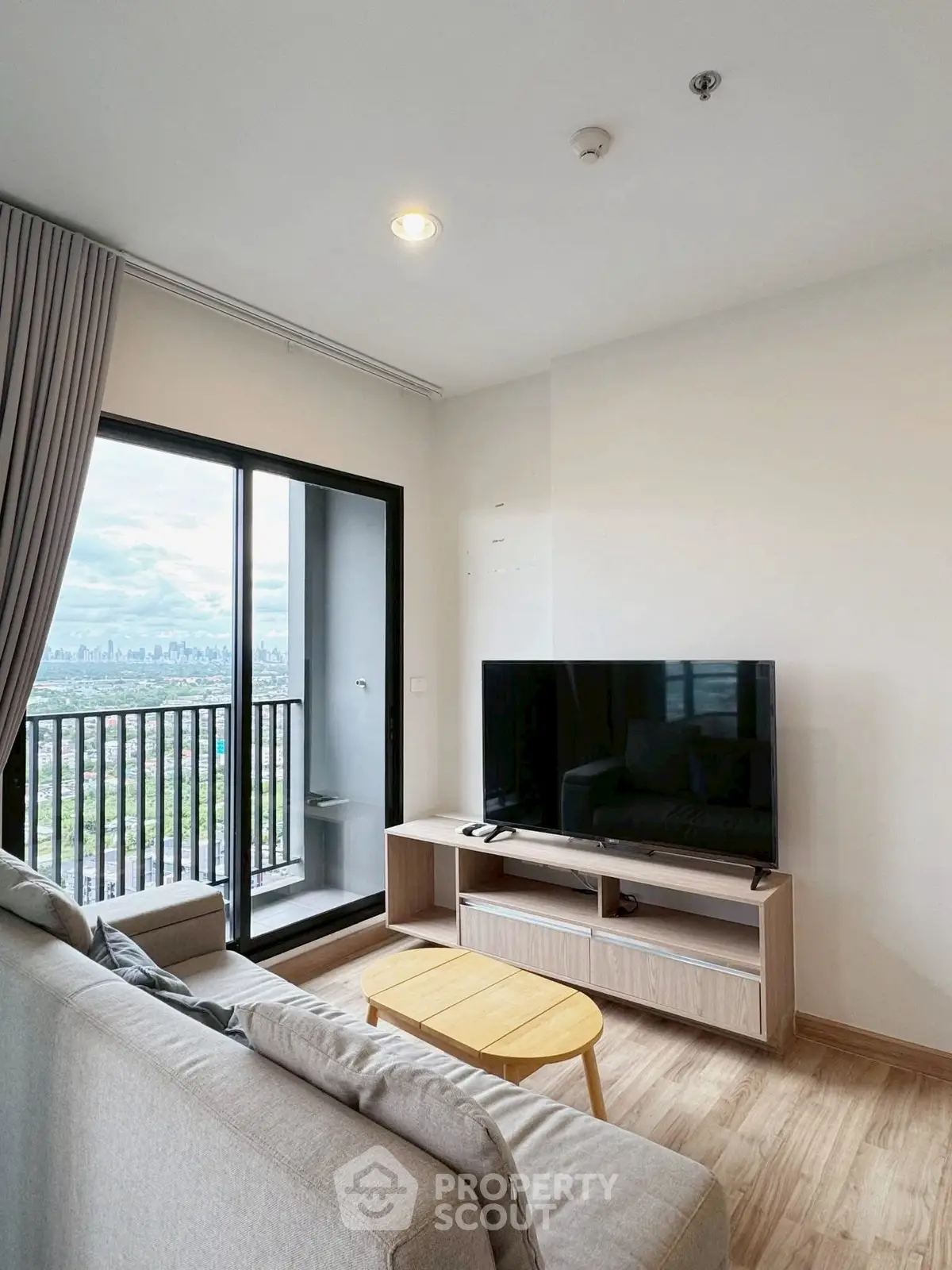 Modern living room with city view balcony, sleek furniture, and natural light.
